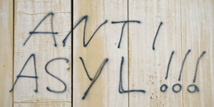 Mit Schwarzer Sprühfarbe stehen die Worte "Anti Asyl" an einer Wand