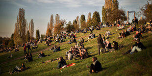 Menschen sitzen an einem Hang im Mauerpark in der Abendsonne