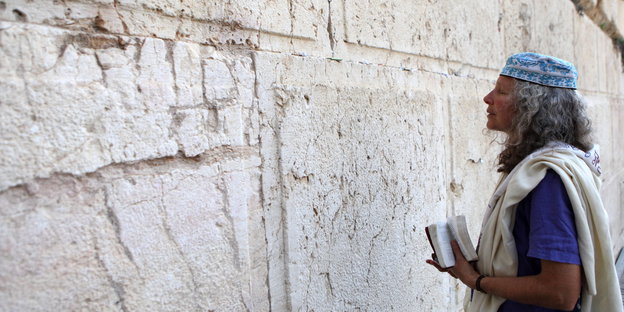 Eine Frau mit einem weißen Schal betet mit geschlossenen Augen an der Klagemauer in Jerusalem