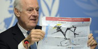 Staffan de Mistura hält einen Plan von Syrien und Irak in die Höhe, im Hintergrund sind Teile des UN-Logos zu sehen.