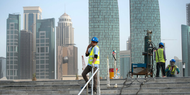 Bauarbeiter auf einer Treppe vor Wolkenkratzern