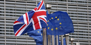 Der britische Union Jack weht neben einer Europafahne vor einem EU-Gebäude.