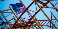 Eine EU- und eine US-Flagge wehen im Wind auf einer Achterbahn.