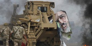An einem Panzer hängt der Rest eines Posters von Mahammed Mursi, davor laufen Soldaten