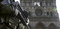 Ein Polizist mit Maschinengewehr steht vor der Notre Dame.