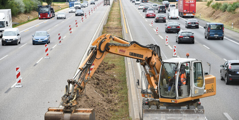 Bagger bearbeitet den Mittelstreifen einer Autobahn.