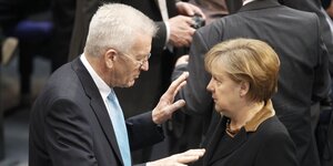 Winfried Kretschmann und Angela Merkel stehen sich gegenüber und schauen sich an.