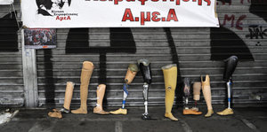 Ein knappes Dutzend Beinprothesen lehnen an einer graffitiverzierten Wand