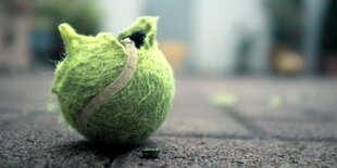 Ein geplatzter Tennisball liegt in urbanem Ambiente