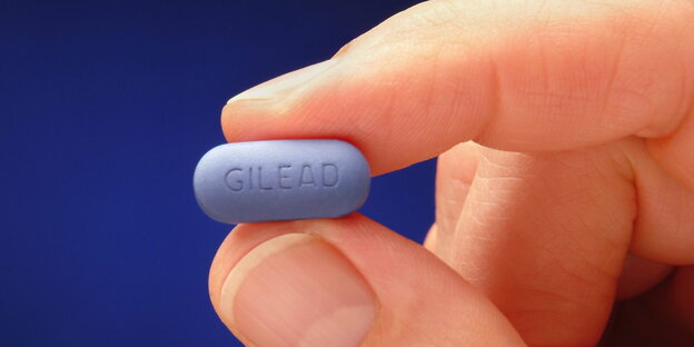 Ein Hand hält ein blaue Truvada-Tablette.