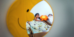 Spiegel in Form eines Mondes zeigt Kind im Bett
