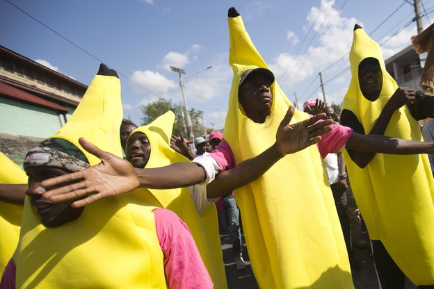 Menschen in Bananenkostümen laufen mit ausgebreiteten Armen