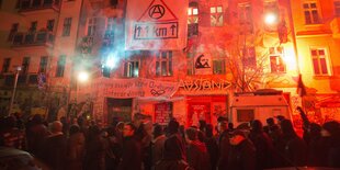 Demonstranten vor einer rot erleuchteten Hausfront