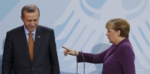 Erdogan links neben Merkel, die mit dem Finger in seine Richtugn zeigt.