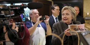 Hillary Clinton hält eine Kaffee-Bestellung in den Händen und wird dabei von Fans gefilmt