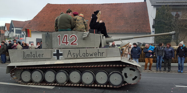 Ein Karnevals-Wagen in Gestalt eines Panzers mit der Aufschrift „Ilmtaler Asylabwehr“ fährt eine Straße entlang