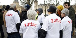 Eine Gruppe Menschen mit weißen Attac-T-Shirts steht im Kreis