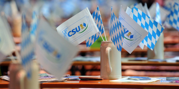 Bierkrüge mit CSU-Flaggen stehen auf einem Tisch.