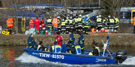 Rettungskräfte sammeln sich an Land und auf einem Boot vor dem verunglückten Zug