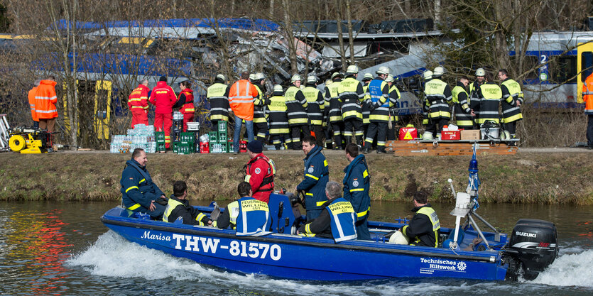 Rettungskräfte sammeln sich an Land und auf einem Boot vor dem verunglückten Zug