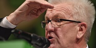 Herr Kretschmann blickt nach vorn, die Hand an der Stirn, um die Sicht zu verbessern