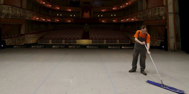 Ein Mann putzt eine Theaterbühne
