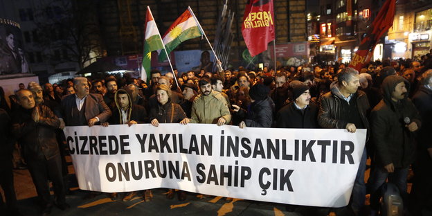 Demonstranten tragen ein Plakat und Fahnen