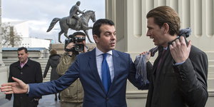 Die zwei Minister im Freien, Popovski gestikuliert, im Hintergrund ein Reiterstandbild.