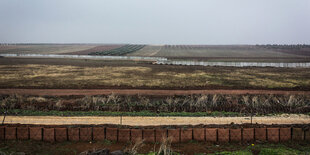 Flaches Land, durchzogen mit Zäunen und Mauern, schlechtes Wetter.