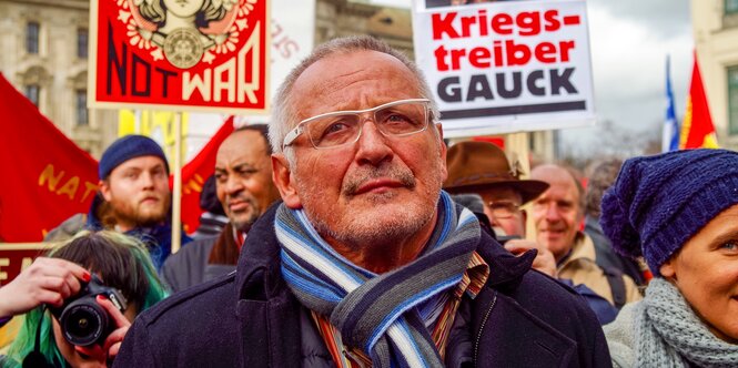 Konstantin Wecker vor Plakaten der DemonstrantInnen.