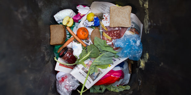 Verschiedene Lebensmittel liegen in einer offenen Mülltonne